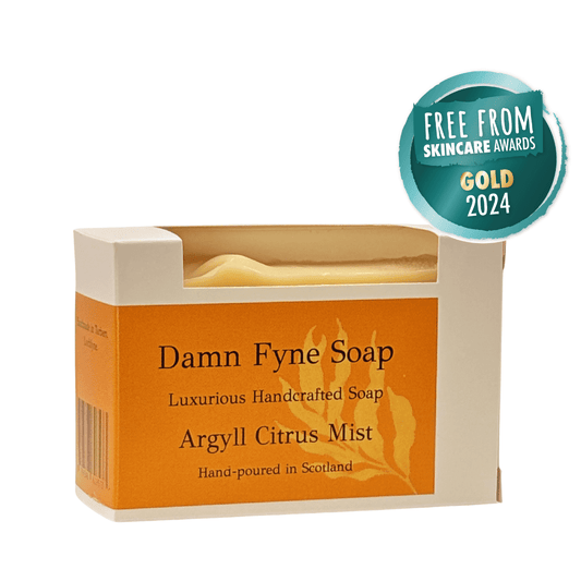 Argyll Citrus Mist handmade soap bar in a kraft box with orange label. Light yellow soap peeks above the packaging. Label reads “Damn Fyne Soap – Luxurious Handcrafted Soap – Argyll Citrus Mist – Hand-poured in Scotland.”