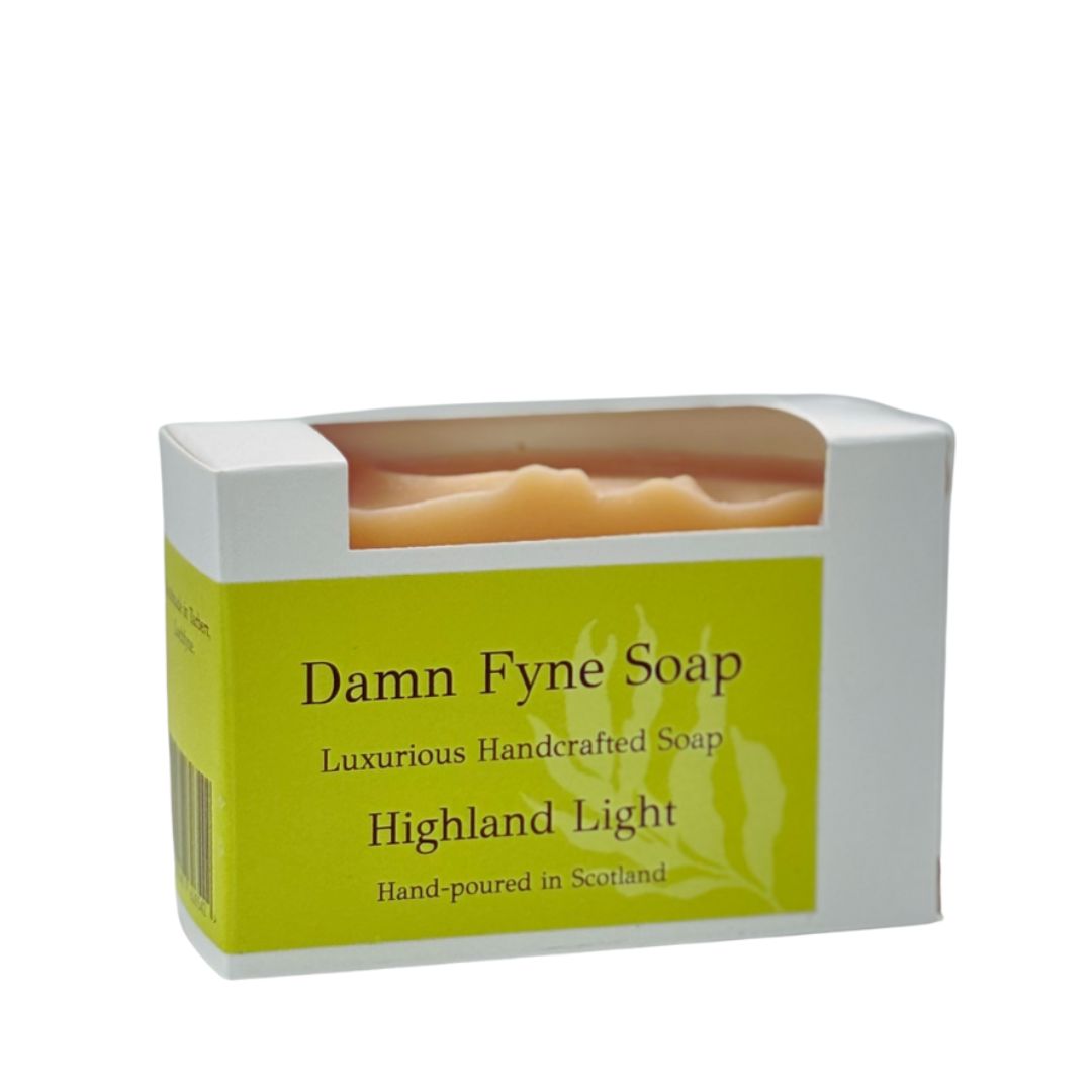 Highland Light handmade soap bar in biodegradable kraft packaging with a golden yellow label. Label reads “Damn Fyne Soap – Luxurious Handcrafted Soap – Highland Light – Hand-poured in Scotland.” Pale-toned soap visible above the box, photographed on a neutral background.