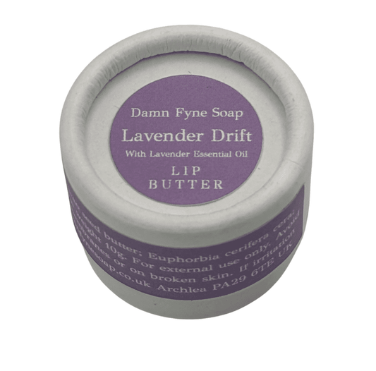 Lavender Drift Lip Butter in a biodegradable cylindrical container with a soft lavender label. Label reads “Damn Fyne Soap – Lavender Drift – With Lavender Essential Oil – Lip Butter.” Photographed from above on a white background, showing the lid and part of the container.