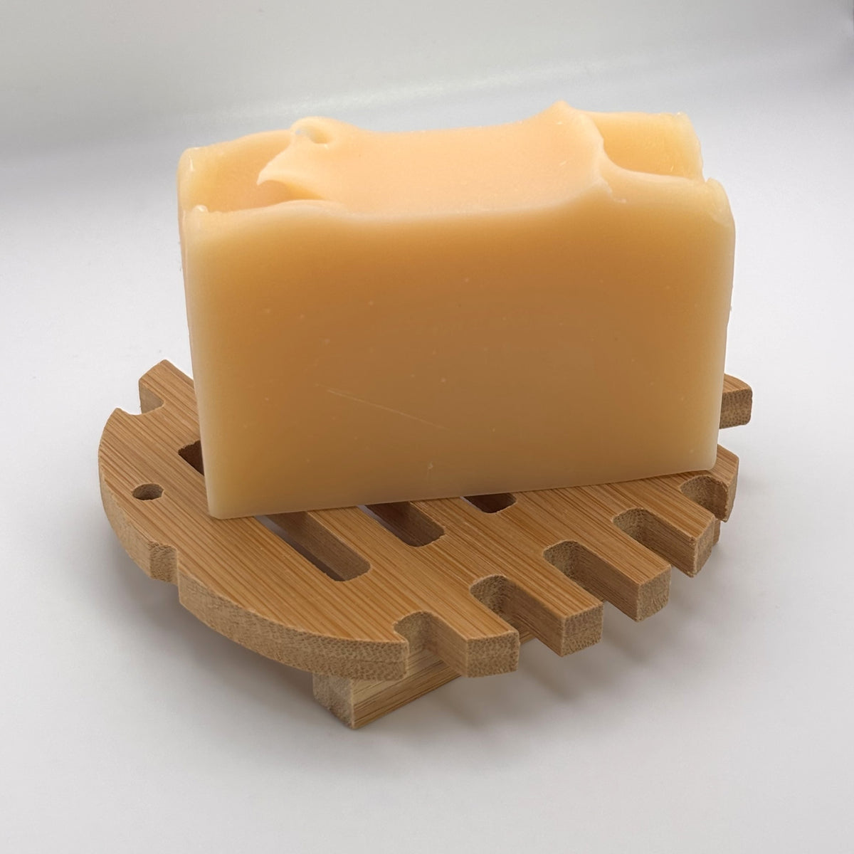 Handmade soap bar resting on a round bamboo draining soap dish