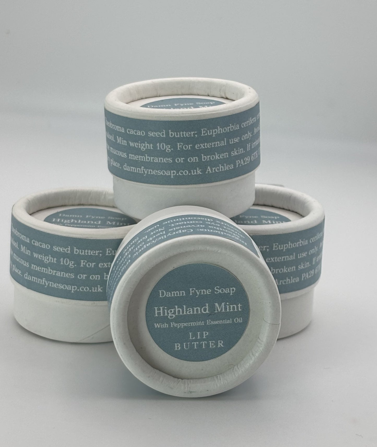 Stack of Highland Mint Lip Butter pots showing biodegradable packaging and handmade Scottish lip balm.