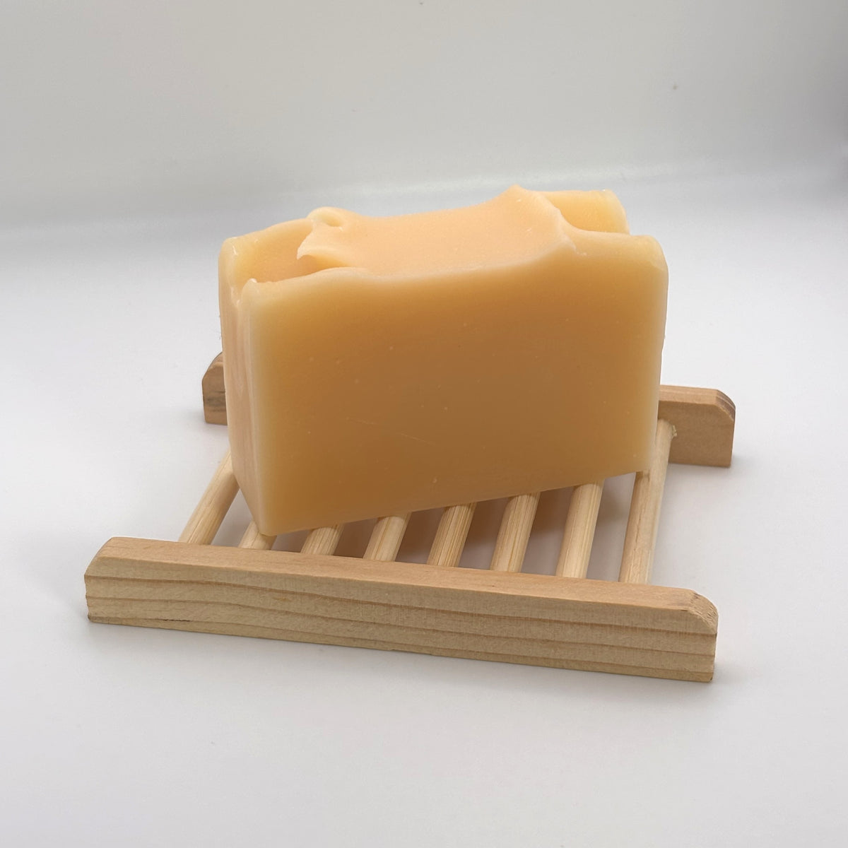 Handmade soap bar resting on a slatted wooden soap dish