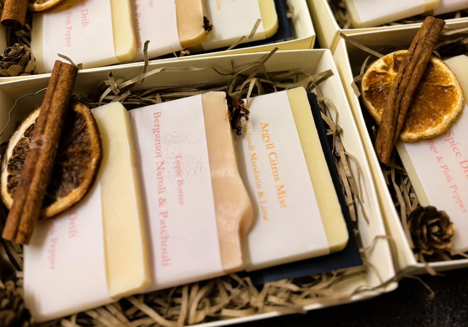 Cream Damn Fyne Soap gift box with navy ribbon, festive trimmings, and three artisanal patchouli blend soaps—Argyll Citrus Mist, Bergamot Patchouli & Neroli, and Fyne Spice Drift.