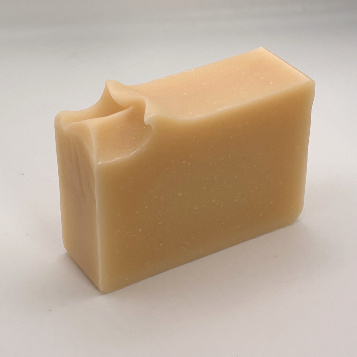 Unwrapped Cedar of Alba handmade soap bar, showing its natural colour and hand-finished top.