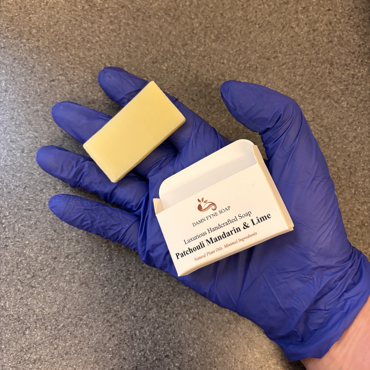 blue gloved hand showing an individual guest soap and box