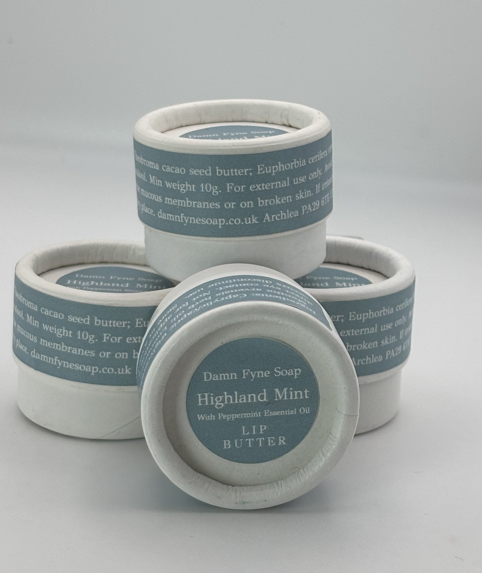 Stack of Highland Mint Lip Butter pots showing biodegradable packaging and handmade Scottish lip balm.