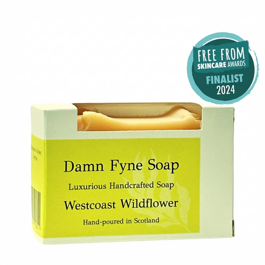 Westcoast Wildflower handmade soap bar in biodegradable kraft packaging with a soft pink label. Label reads “Damn Fyne Soap – Luxurious Handcrafted Soap – Westcoast Wildflower – Hand-poured in Scotland.” Pale-toned soap visible above the box, photographed on a neutral background. rose geranium and lemongrass essential oils.
