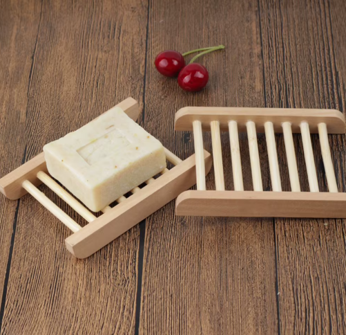 Natural wooden soap dish with slatted drainage design holding a handmade soap bar.